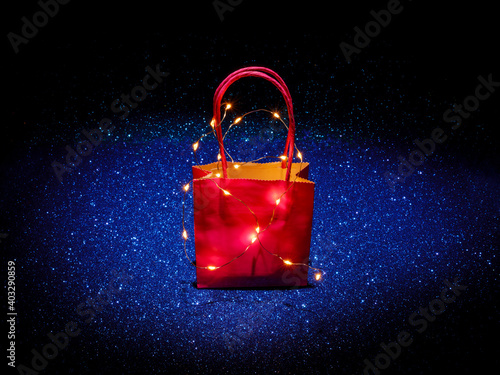 Shopping bag on glitter background texture sparkling. For gifts, deals, sales, event or Christmas holiday seasonal decoration. Online sales concept.