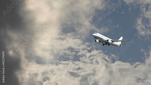 Zoom photo of passenger airplane taking off in deep blue slightly cloudy sky as seen from the ground 
