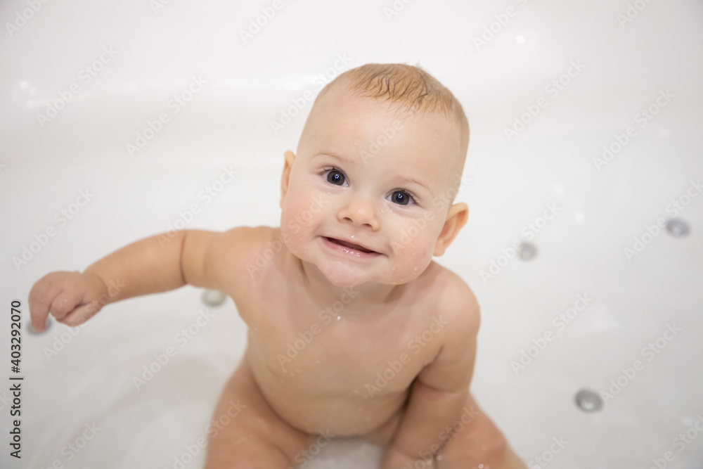 Cute baby girl bathing with toys and smiling in a big white bath Cute baby girl bathing with toys and smiling in a big white bath