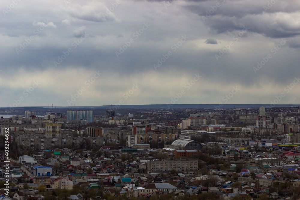 Panoramic view of the Russian city. A view of the city in cloudy weather with one clearing through which the sun's rays beat. 