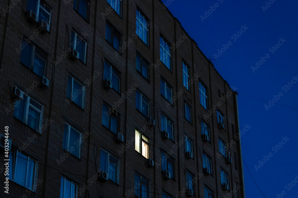 One luminous window in a multi-storey building at night.