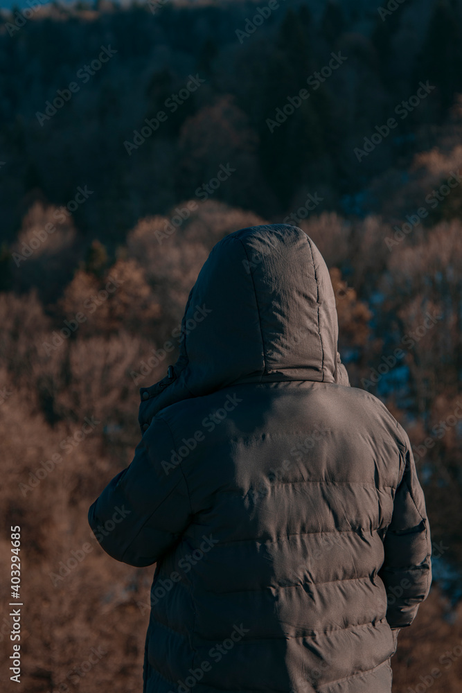 The guy in the jacket stands against the background of the forest. Travel and Leisure. Forest landscape. The guy in the jacket stands against the background of the forest. Travel and Leisure. Forest landscape.