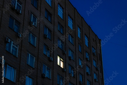 One luminous window in a multi-storey building at night.