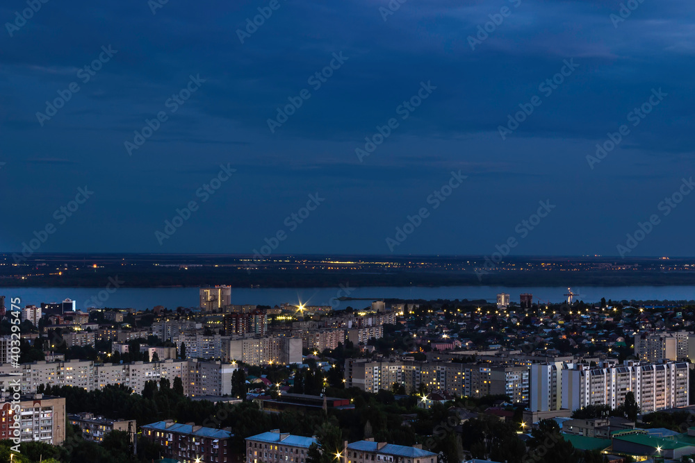 Fototapeta premium View of the city with high-rise buildings against the background of the river and sunset.