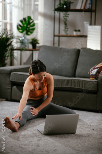 Athletic woman in sportswear doing stretching exercises at home in the living room. Fit woman training at home. © JustLife