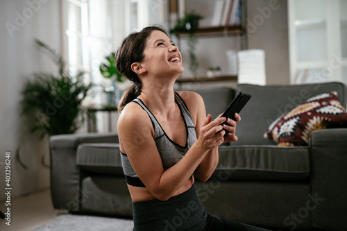 Athletic woman having video call. Young girl talking while doing stretching exercises at home