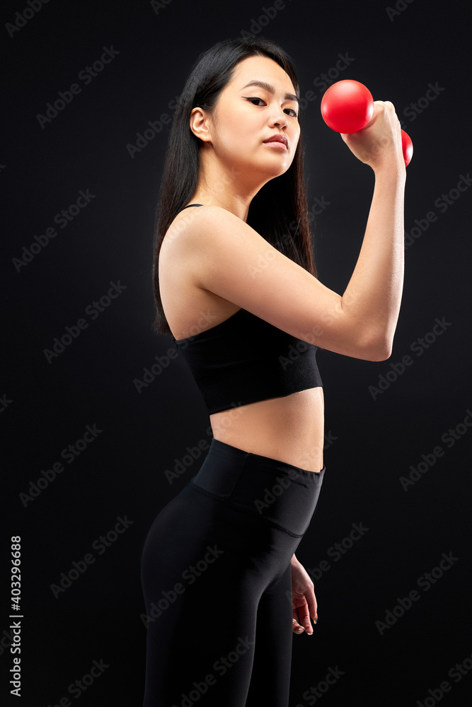 sportswoman holding dumbbells in hands, having strong muscular biceps, pumping arm muscles, isolated on black background sportswoman holding dumbbells in hands, having strong muscular biceps, pumping arm muscles, isolated on black background