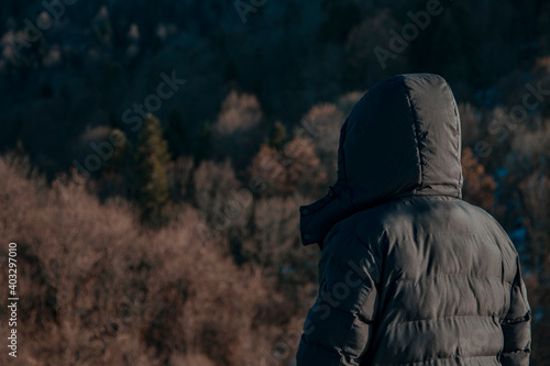 The guy in the jacket stands against the background of the forest. Travel and Leisure. Forest landscape. © Denis