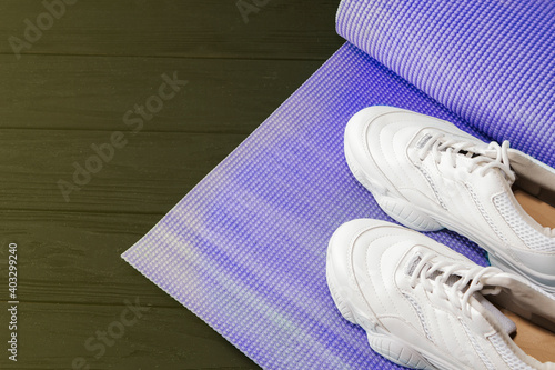 yoga mat and sports shoes on a black background. Healthy lifestyle, yoga, the concept of s.ports