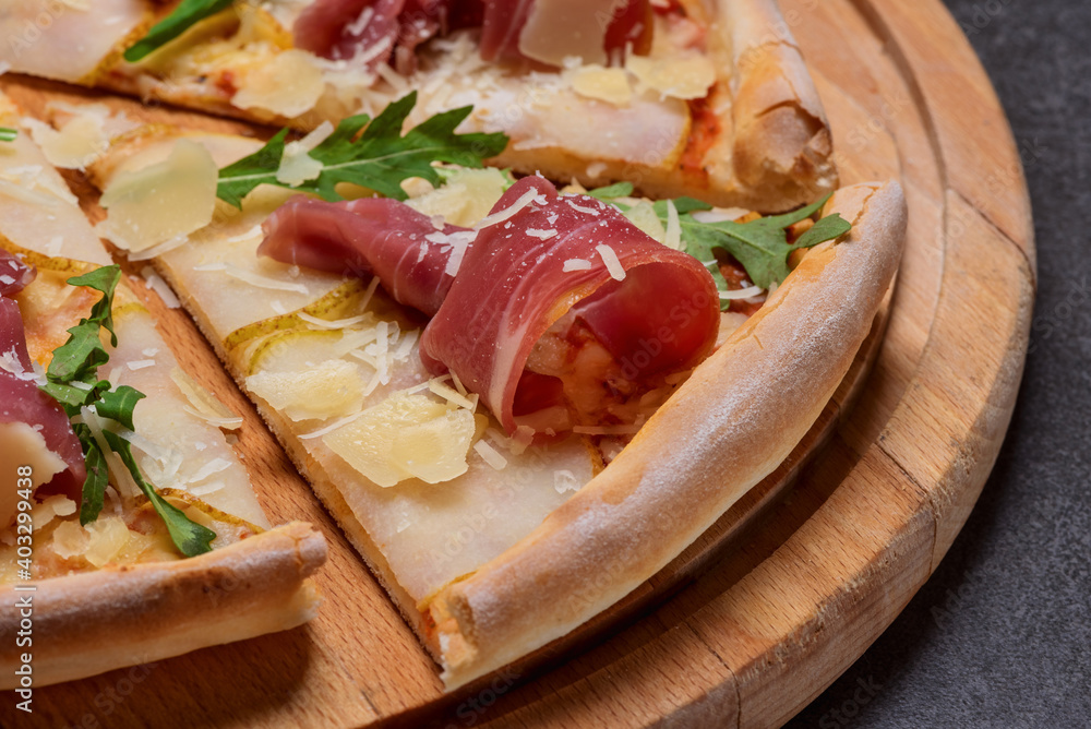 Italian pizza with sliced prosciutto ham, cheese, and fresh green rocket leaves closeup Italian pizza with sliced prosciutto ham, cheese, and fresh green rocket leaves closeup