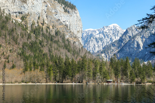 Leopoldsteiner lake in Austria. The lake is surrounded by high Alps. The shallow water is crystal clear  spring water has a calm surface. Early spring. Glacier in the back. Calmness and nostalgia