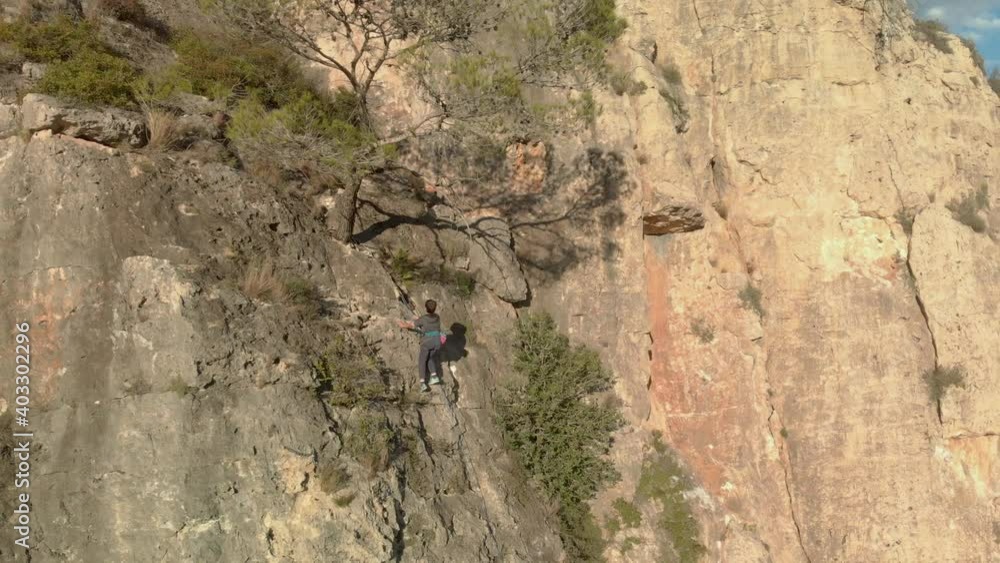 Aerial shot moving away from a child climber to show a very general plan of the mountain. Aerial shot moving away from a child climber to show a very general plan of the mountain.