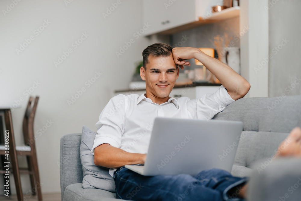 smiling young man browsing Internet while lying on the couch. smiling young man browsing Internet while lying on the couch.