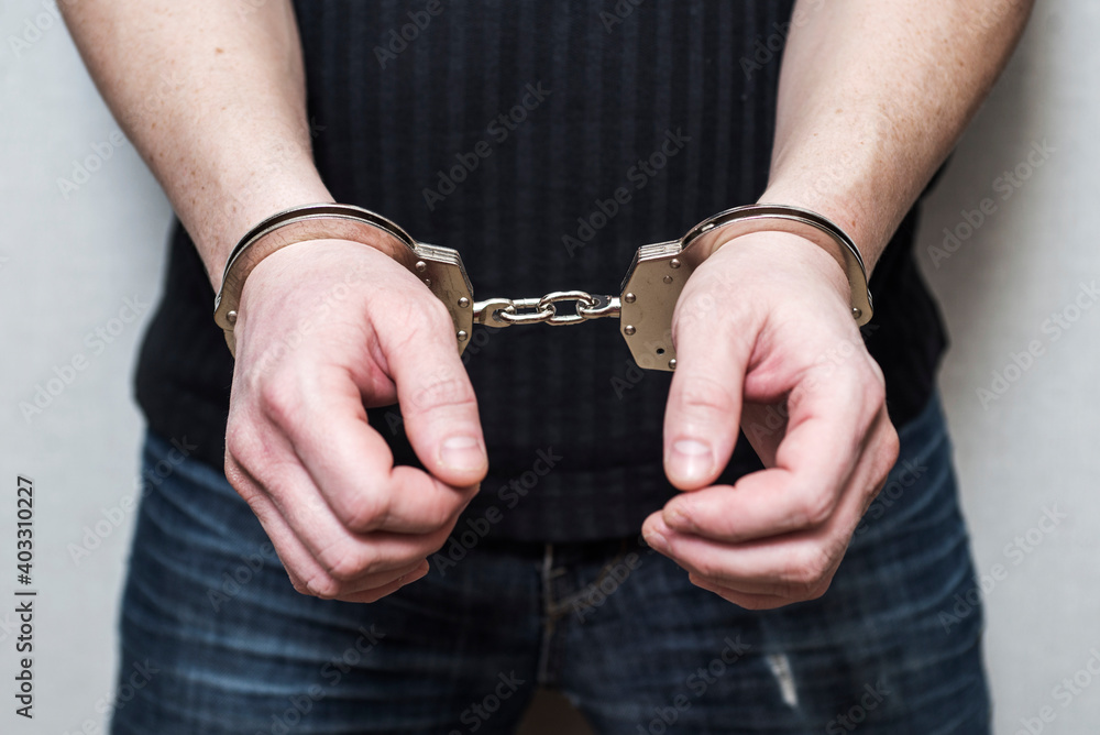 Man detained in handcuffs. Prisoner or arrested man in handcuffs. Male hands in handcuffs. Criminal law Man detained in handcuffs. Prisoner or arrested man in handcuffs. Male hands in handcuffs. Criminal law