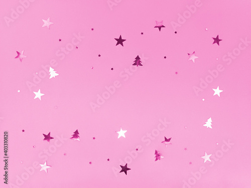 Confetti stars and trees sparkling on pink background.