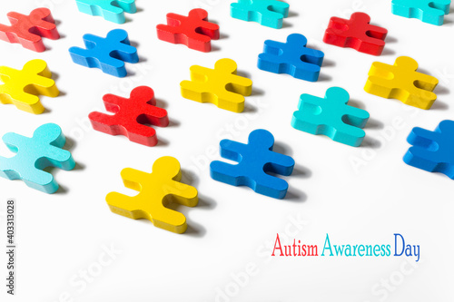 Four colors wooden dolls of children isolated on white background with inscription Autism Awareness Day. World Autism Awareness day concept.