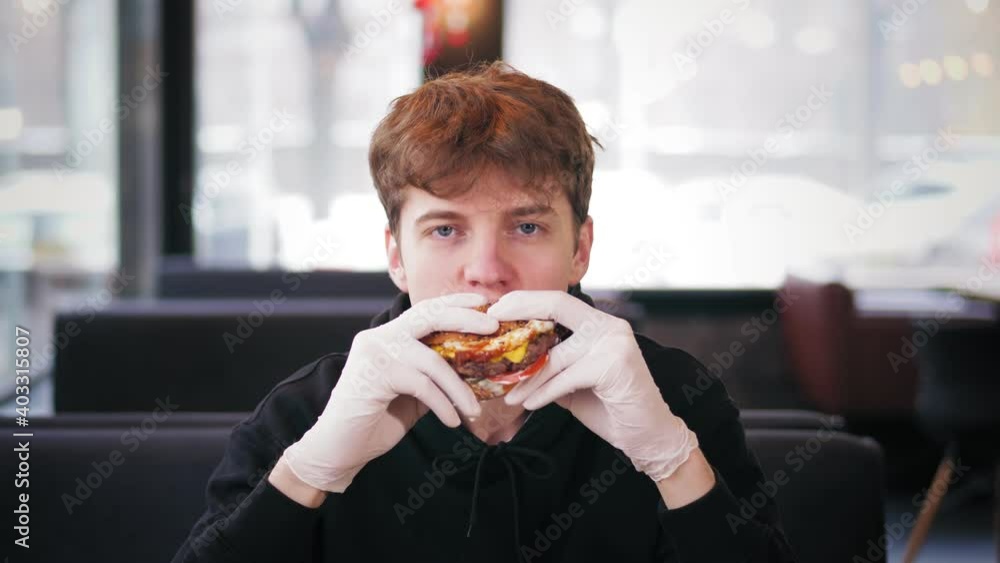 fast food, junk food. portrait. young handsome guy eating juicy, tasty, freshly prepared, fatty burger, hamburger, with appetite. fast food, junk food. portrait. young handsome guy eating juicy, tasty, freshly prepared, fatty burger, hamburger, with appetite.