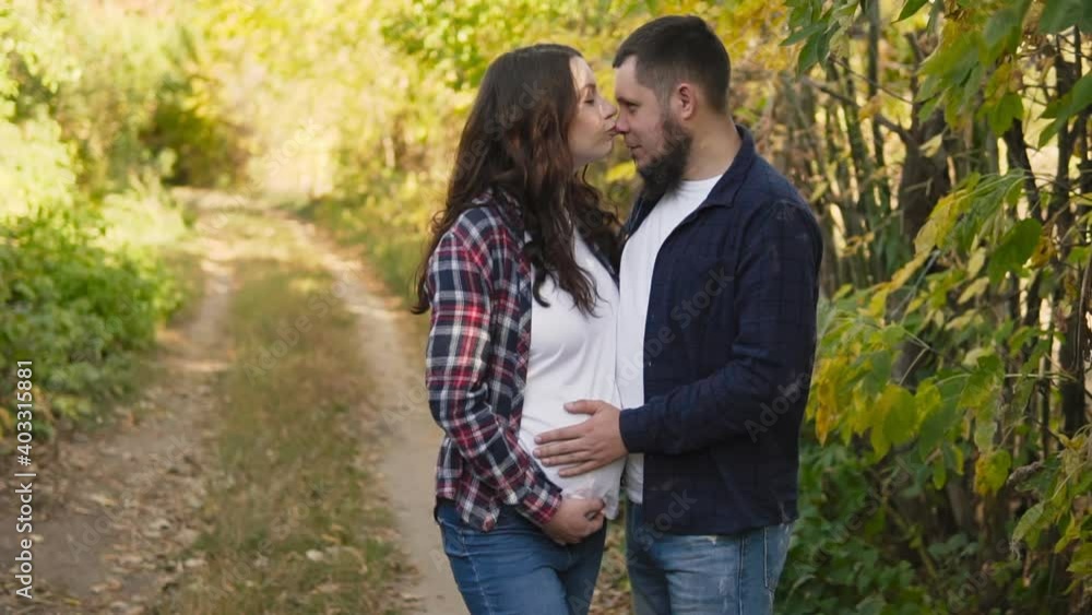 Young expectant parents, happy couple gently holds hands standing on the forest path. Young expectant parents, happy couple gently holds hands standing on the forest path.
