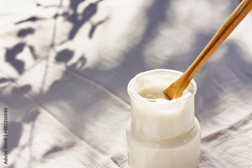 Fresh natural organic yogurt in a glass jar on white tablecloth with leaf shadows. Natural light. Healthy breakfast. Fresh natural organic yogurt in a glass jar on white tablecloth with leaf shadows. Natural light. Healthy breakfast.