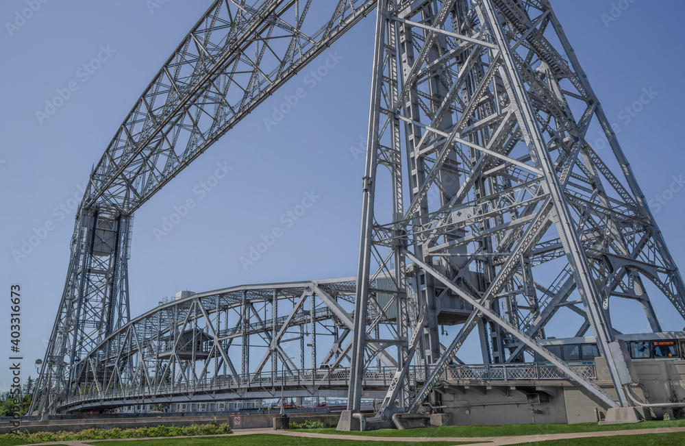 Lift Bridge: Vertical tracks allow the center portion of a large bridge to permit the flow of traffic when lowered, or to raise upward and allow passage of tall boats through a harbor in Duluth, MN. Lift Bridge: Vertical tracks allow the center portion of a large bridge to permit the flow of traffic when lowered, or to raise upward and allow passage of tall boats through a harbor in Duluth, MN.