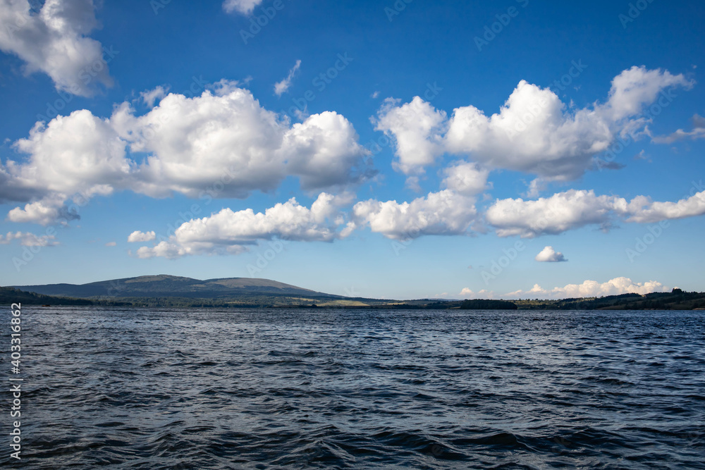 Obraz premium View from a boat of Vlasina lake with clouds on the blue sky
