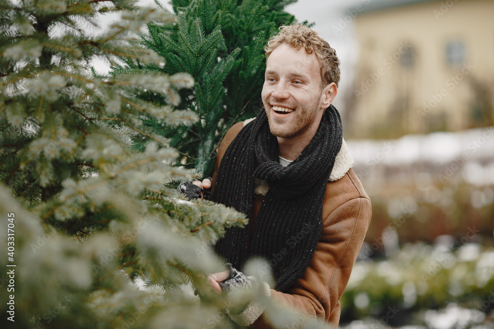Winter concept. Guy in a brown coat. Salesman of Christmas Tree. Winter concept. Guy in a brown coat. Salesman of Christmas Tree.