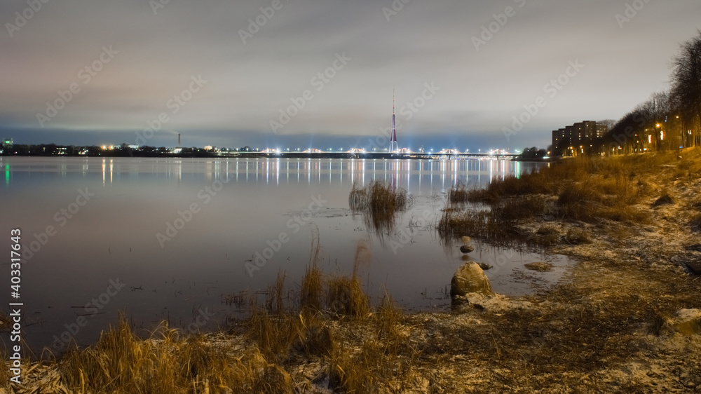 Evening landscape. the bank of the Dvina River in the distant plan lights of the city