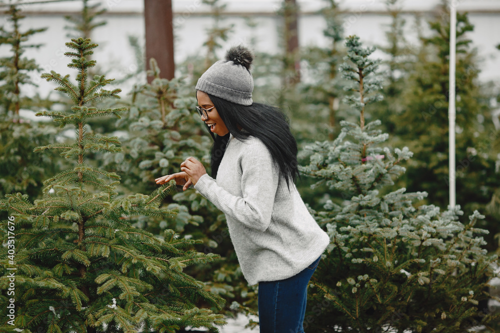 Winter concept. Woman in a gray sweater. Saleswoman of Christmas Tree.