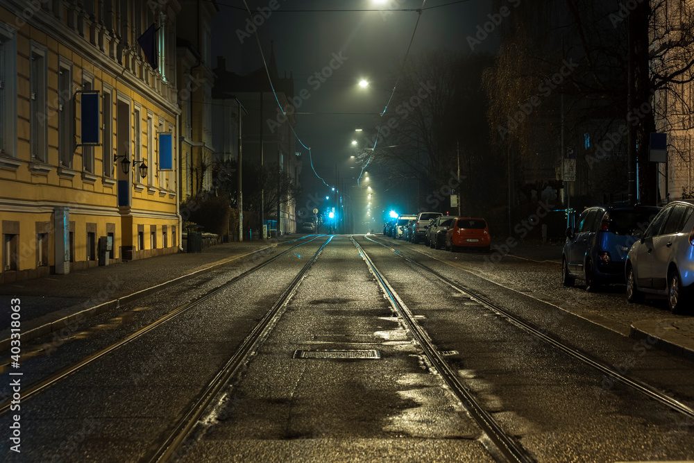 Old Norwegian central street with tram paths lit by soft night lights.