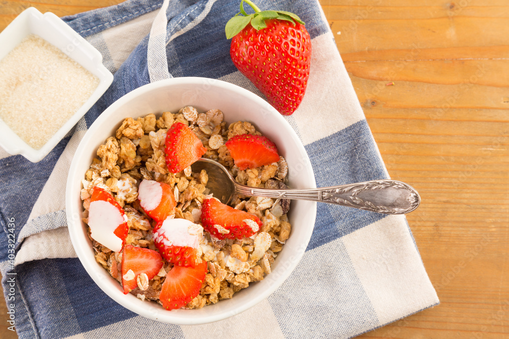 Bowl of cereals with strawberries resting on a blue napkin Bowl of cereals with strawberries resting on a blue napkin