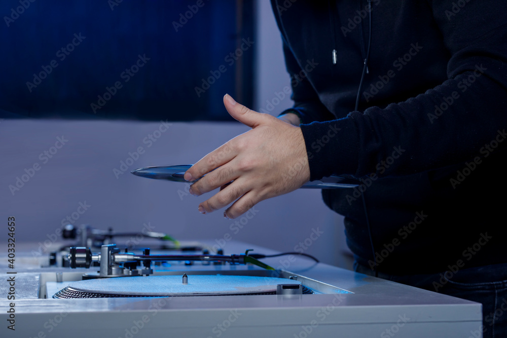 Dj colocando un disco de vinilo en su tocadiscos mientras mezcla música en una tienda de discos. Concepto de música retro Dj colocando un disco de vinilo en su tocadiscos mientras mezcla música en una tienda de discos. Concepto de música retro