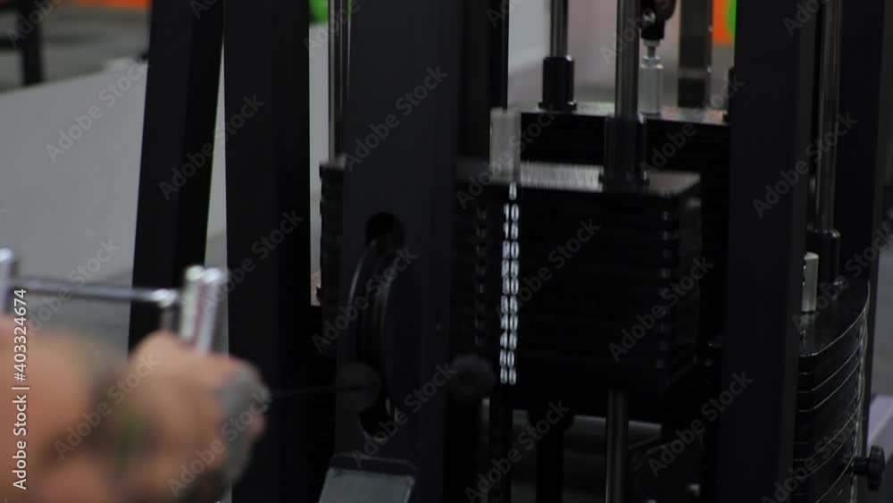 Young man works out in the gym. Serious, focused. Shakes shoulders, arms and chest on the simulator. Pulls on yourself. Young man works out in the gym. Serious, focused. Shakes shoulders, arms and chest on the simulator. Pulls on yourself.