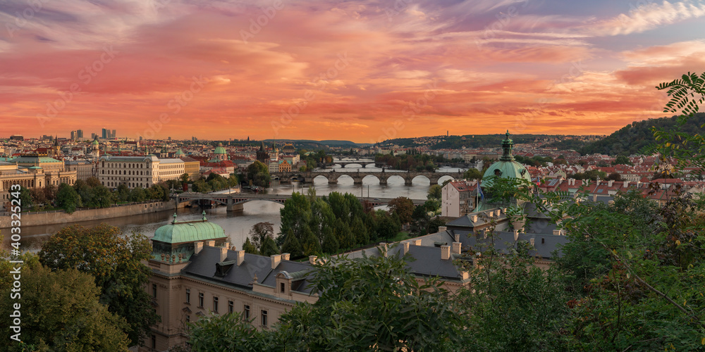 .panorama of the city of Prague in the spring and bridges on the Vltava river between them and the Charles Bridge and the roofs of buildings during the day orange sky 