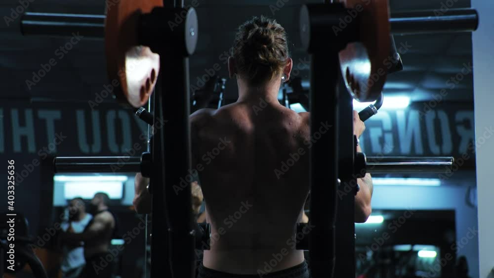 Young man works out in the gym. Serious, focused. Shakes shoulders, arms and chest on the simulator. Push Young man works out in the gym. Serious, focused. Shakes shoulders, arms and chest on the simulator. Push