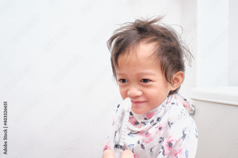 Asian Parent flushing her sick happy little toddler baby girl child nose with syringe for nasal Irrigation, Saltwater Washes - Selective focus at kid's right eye Asian Parent flushing her sick happy little toddler baby girl child nose with syringe for nasal Irrigation, Saltwater Washes - Selective focus at kid's right eye