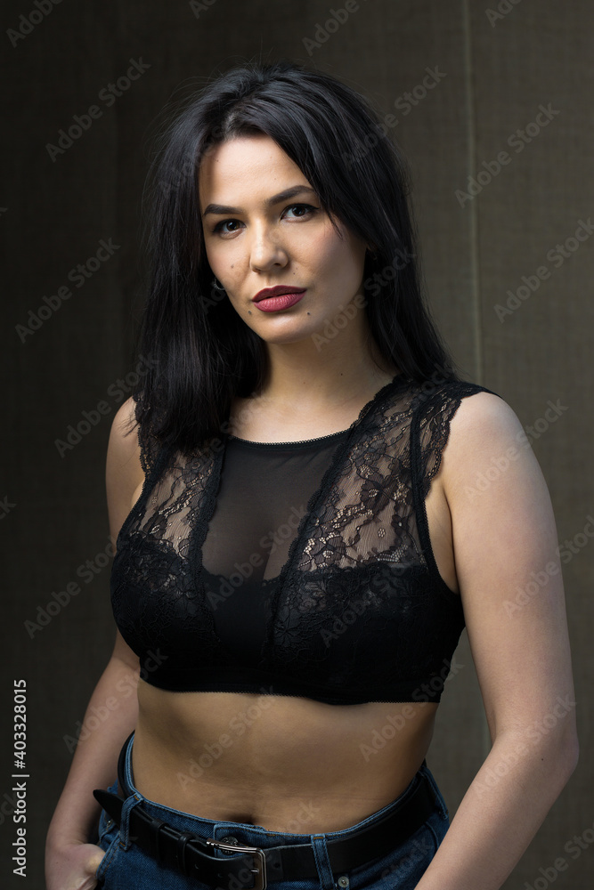 Portrait of a young sexy brunette girl in a lace top in dramatic tones. Vintage photo.