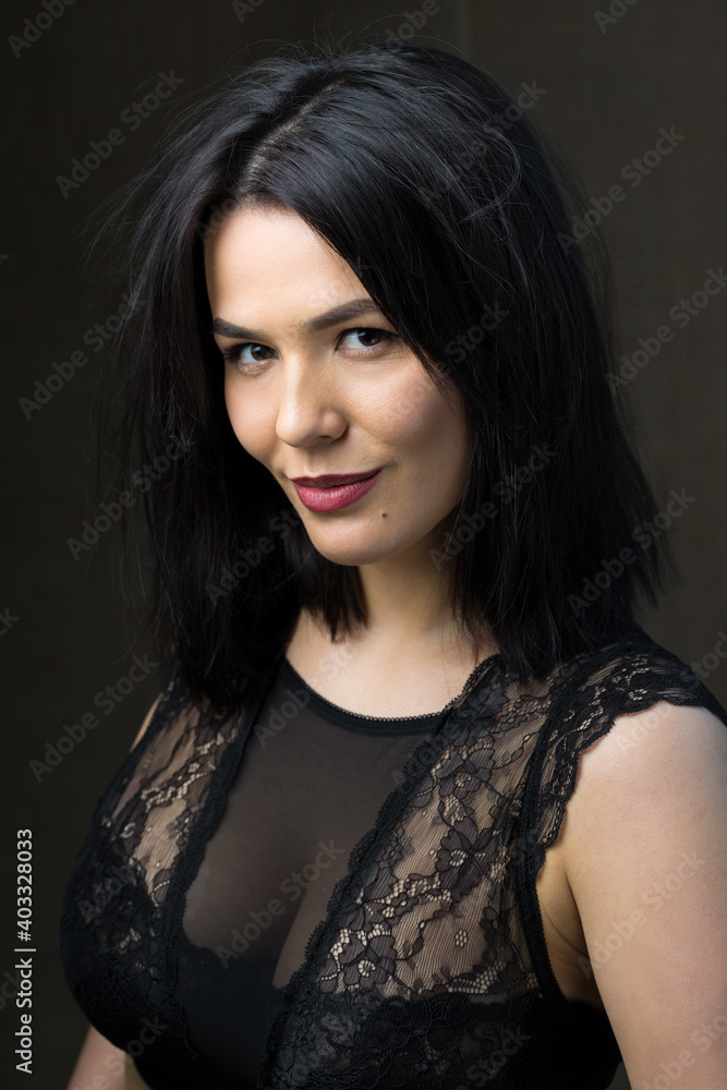 Portrait of a young sexy brunette girl in a lace top in dramatic tones. Vintage photo.