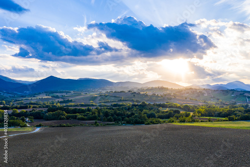 Aerial view of warm sunset on the hills surrounding Fabriano, Marche, Italy. It's summer and the sun is lighting the cultivated fields. photo