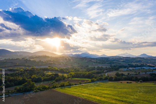 Aerial view of warm sunset on the hills surrounding Fabriano, Marche, Italy. It's summer and the sun is lighting the cultivated fields. © anna pozzi
