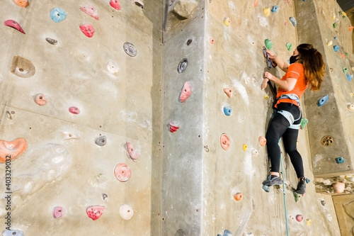 Young fit woman climbing on indoor rock wall. Aerial cinematic footage . High quality photo.