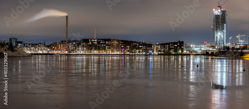 Beautiful night cityscape of Sompasaari residential district casting reflections on the thin icecap on the water.