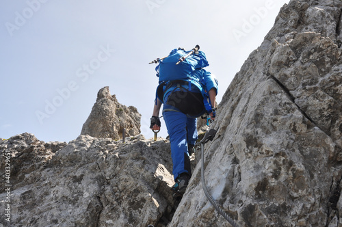 Dziewczyna ubrana na niebiesko pokonuje skalne trudności na via ferracie w Dolomitach