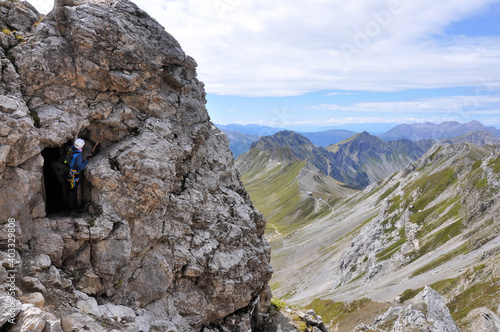 Męzczyzna podziwia górskie widoki z okna wydrążonego w skale, Dolomity photo