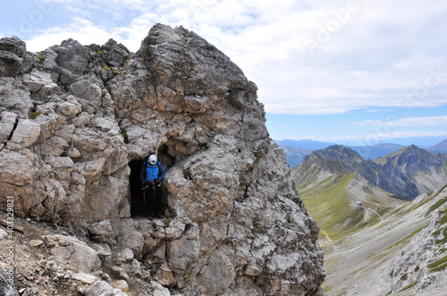 Człowiek stoi w skalnym otworze na szczycie góry podczas wspinaczki na via ferrata, Dolomity