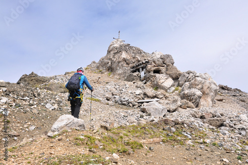 Męzczyzna podchodzi górskim zboczem na szczyt, Dolomity