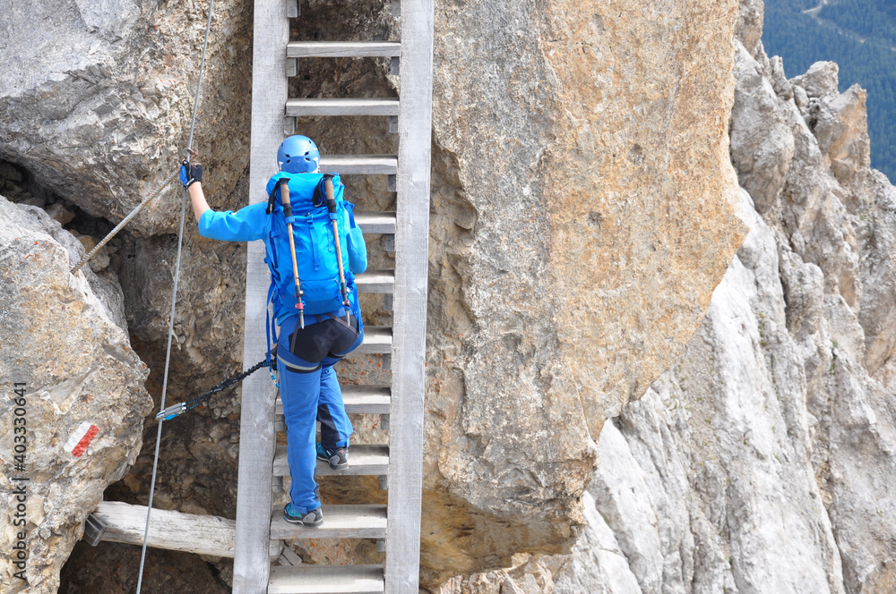Dziewczyna wspina sie po drabinie na via ferracie w Dolomitach, Włochy