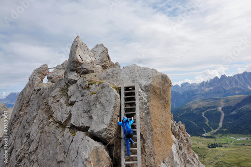 Dziewczyna ubrana na niebiesko wchodzi po drabinie na via ferracie, Dolomity