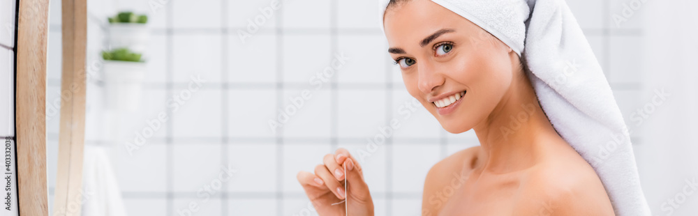 cheerful woman with white terry towel on head looking at camera while holding dental floss, banner cheerful woman with white terry towel on head looking at camera while holding dental floss, banner