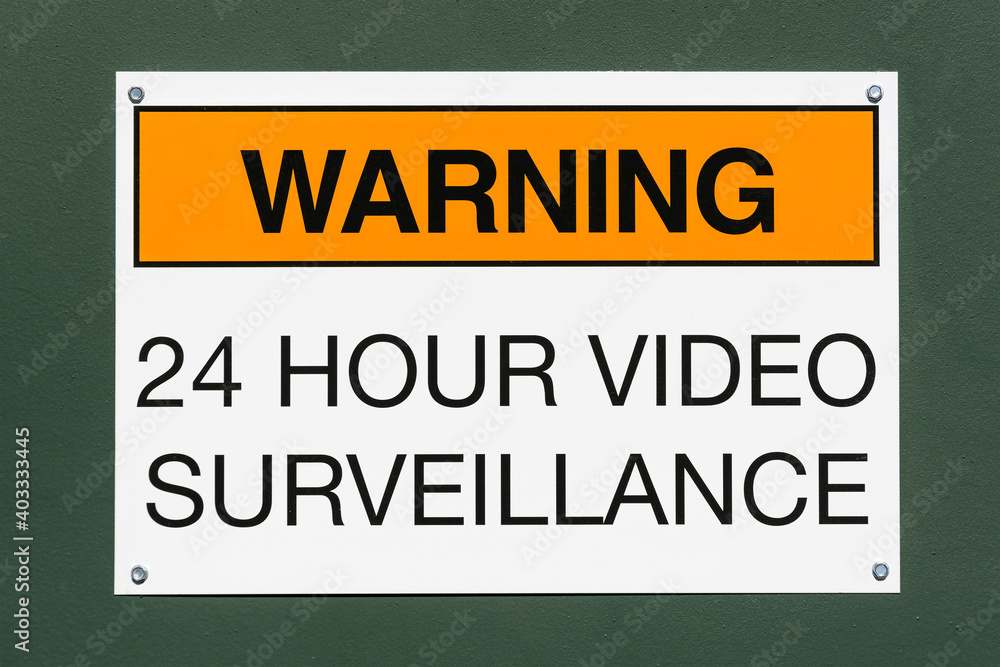 Warning 24 hour video surveillance sign on green metal background.  