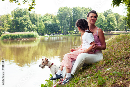 young pretty caucasian mother walking with little cute daughter and dog fox terrier, lifestyle people concept © iordani